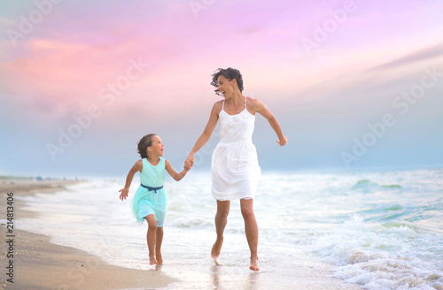 Mother and her daughter runing and having fun on the beach