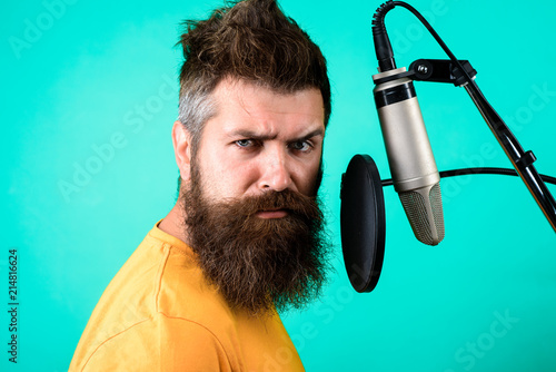 Brutal bearded singer with microphone on stage. Bearded man singing with microphone. Concert&music concept. Male lead vocalist singing in recording studio. Vocalist singing into condenser microphone.