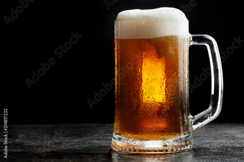 Mug of cold craft light beer on dark background..