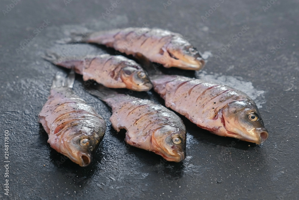 Carp in spices on a black table close-up. Top view. Carp in spices on a black table close-up. Top view.