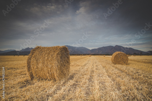 Panoramic views of a brilliant sunset over a meadow with big hay bales. © Dewald