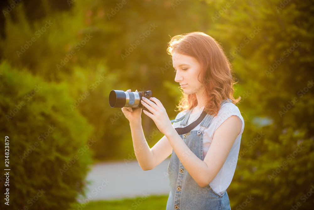 Red-haired girl with a camera taking pictures in the Park Red-haired girl with a camera taking pictures in the Park
