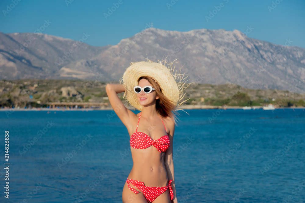 Young redhead girl in hat and bikini on Elafonissi beach, west Crete, Greece. Summertime season