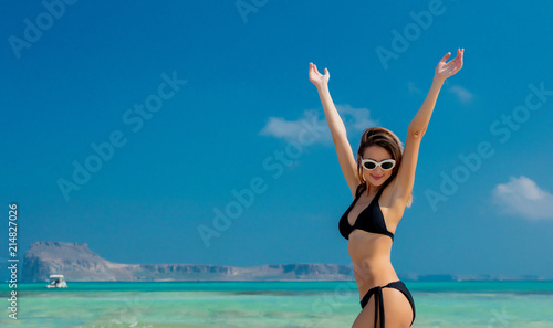 Young redhead girl in black bikini on Balos beach, west Crete, Greece. Summertime season vacation, July