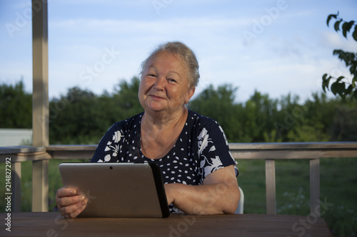 Portrait of senior woman with tablet computer on veranda outdoors