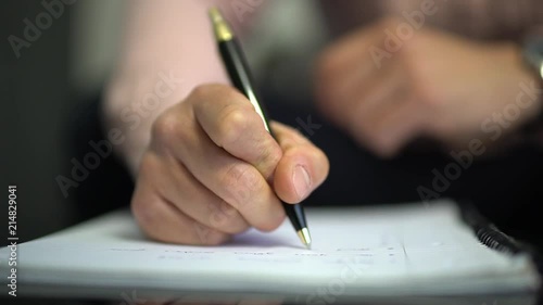 A clip of a man taking notes on a piece of paper in slow-motion CLOSE UP from the FRONT.