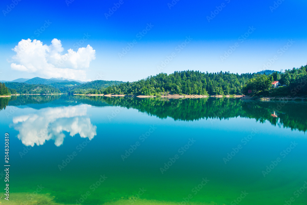 Fototapeta premium Green lake in Gorski kotar, Lokve, Croatia, with Risnjak mountain in background, reflection in watter