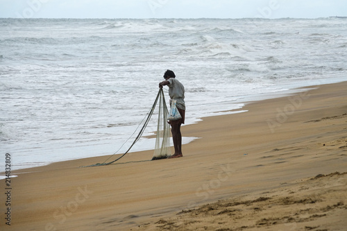 Wadduwa, Sri Lanka - May 08, 2018: A fisherman with fishing net on the beach in Sri Lanka photo