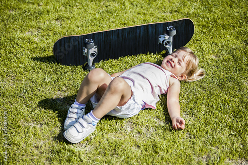 Photography Little blonde girl playing with skateboard in forest park