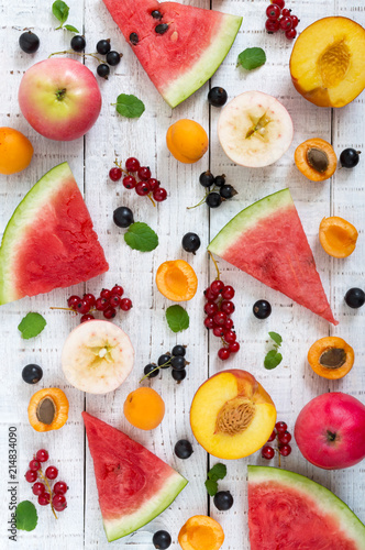 Berry background. Many summer fruits and berries are scattered on a white wooden background. The concept of healthy dietary nutrition. Top view. Flat lay. Banner.