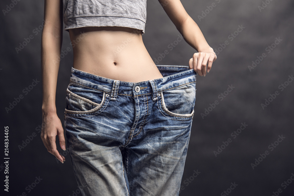 A close up of a slim girl in a gray tank top holding her big size