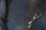 Two Forks and Gray Napkin on the Dark Stone Background