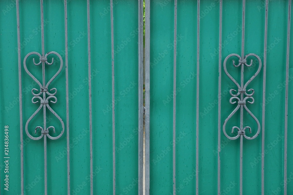 gray forged pattern of steel rods on an iron green fence