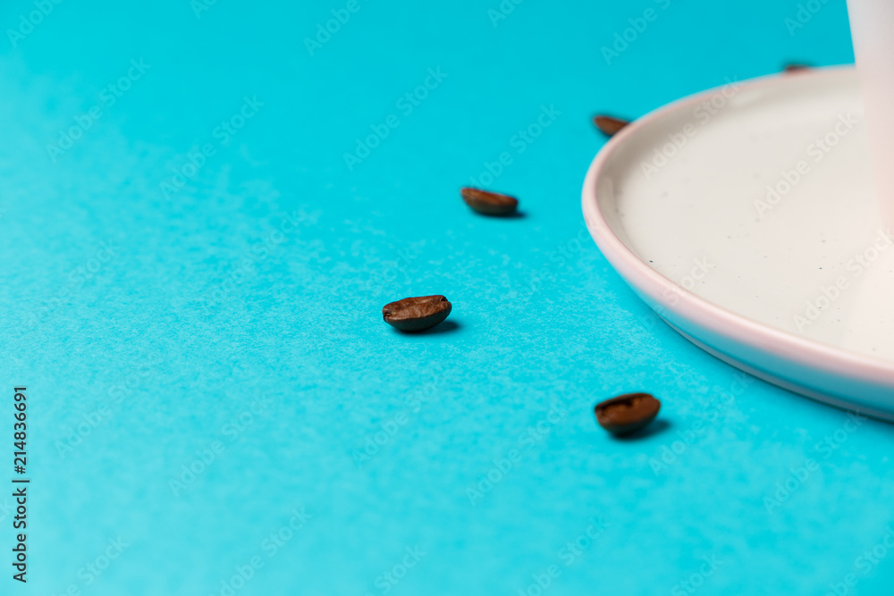 Coffee cup with spoon on saucer and coffee beans against blue background forming clock dial. Coffee as symbol of morning energy and cheerfulness or evening refreshment. Close up. Concept Coffee cup with spoon on saucer and coffee beans against blue background forming clock dial. Coffee as symbol of morning energy and cheerfulness or evening refreshment. Close up. Concept
