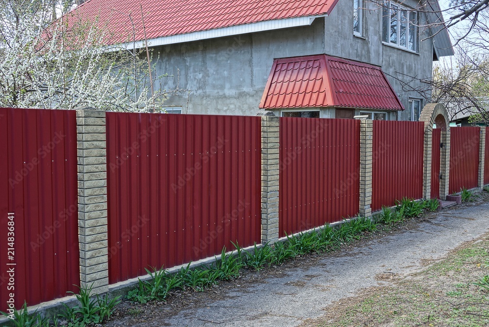 part of a red metal fence and a gate on the street part of a red metal fence and a gate on the street