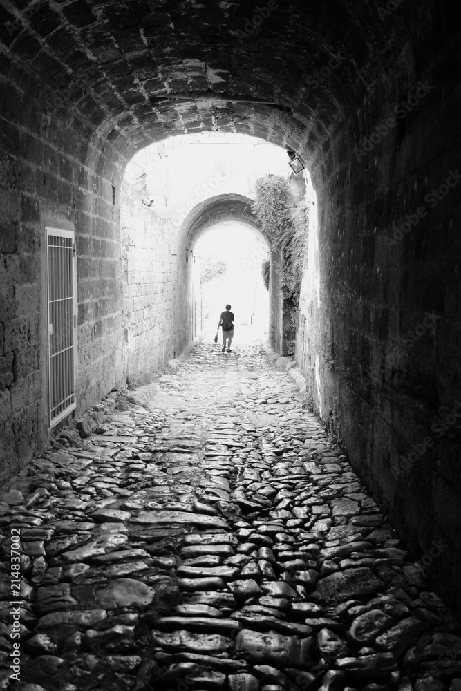Female silhouette in the gleam of an arch of an old house in an ancient city. Bari, Italy