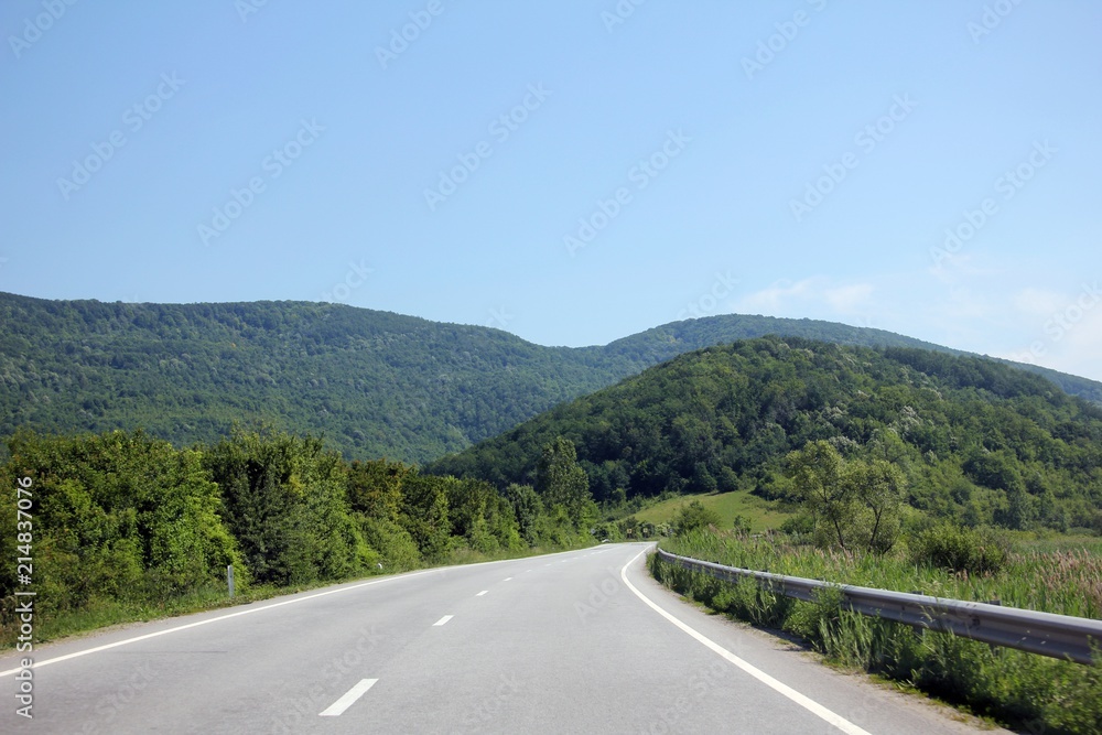 Road passing through gorgeous green hills - preserved environment. 