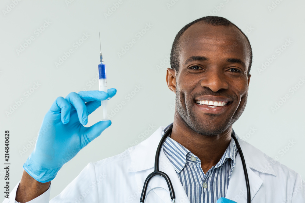 Smiling afro american doctor holding a syringe Smiling afro american doctor holding a syringe