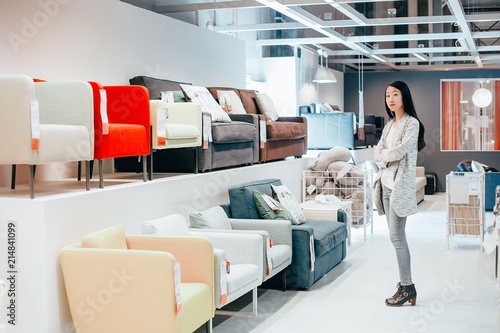 Принти на полотні Beautiful girl choosing armchair in furniture store