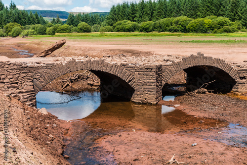 An old,normally submerged bridge in a dried up reservoir in the UK during a drought and heat wave photo