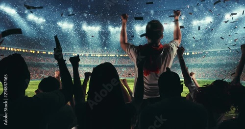 Fans celebrating the success of their favorite sports team, a man is standing with raised hands on the stands of the professional stadium while it's snowing. Stadium is made in 3D and animated.