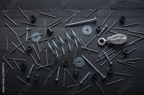 Metal still life of nails, springs, screws and washer hardware on a piece of slate.