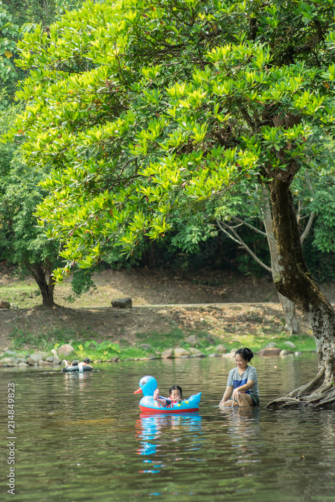 Mother and daughter playing on stream with green tree Mother and daughter playing on stream with green tree