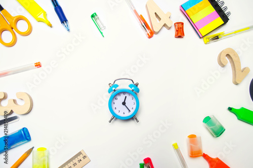 back to school. blue alarm clock on the school desk. stationery. accessories. White background. stickers, colored pens, pencils, scissors. view from above. flat lay. copy space