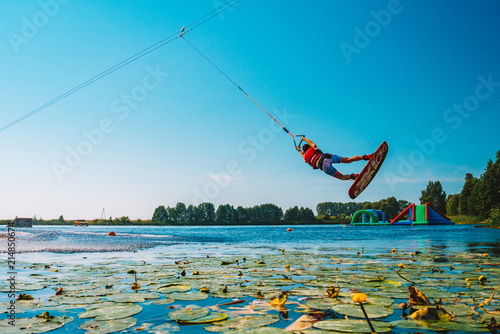 Photography Young man wakeboarding on a lake, making raley, frontroll and jumping the kickers and sliders
