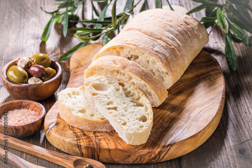 Photos Olives and feta cheese, bread ciabatta,  on olive wood cutting board