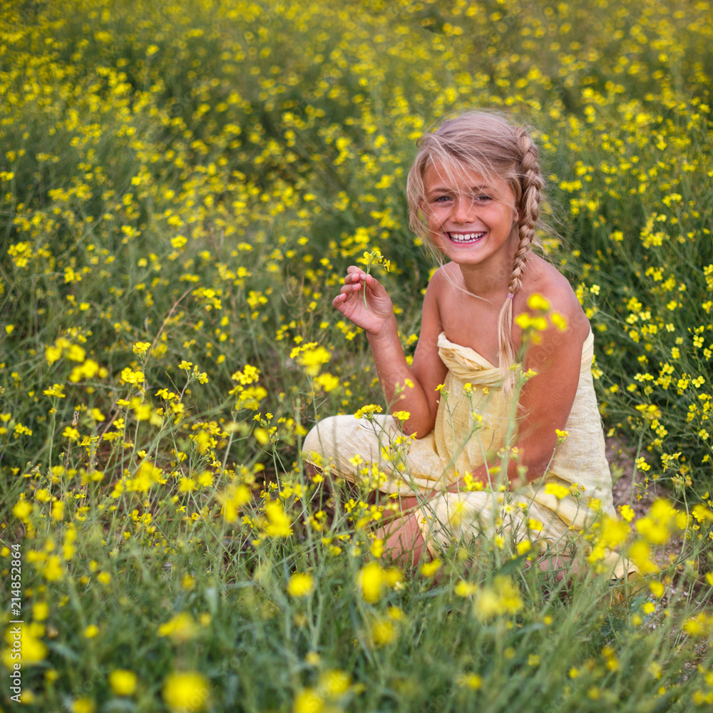 Portrait of happy little girl in field of yellow blossoming arugula. Travel and recreation Portrait of happy little girl in field of yellow blossoming arugula. Travel and recreation