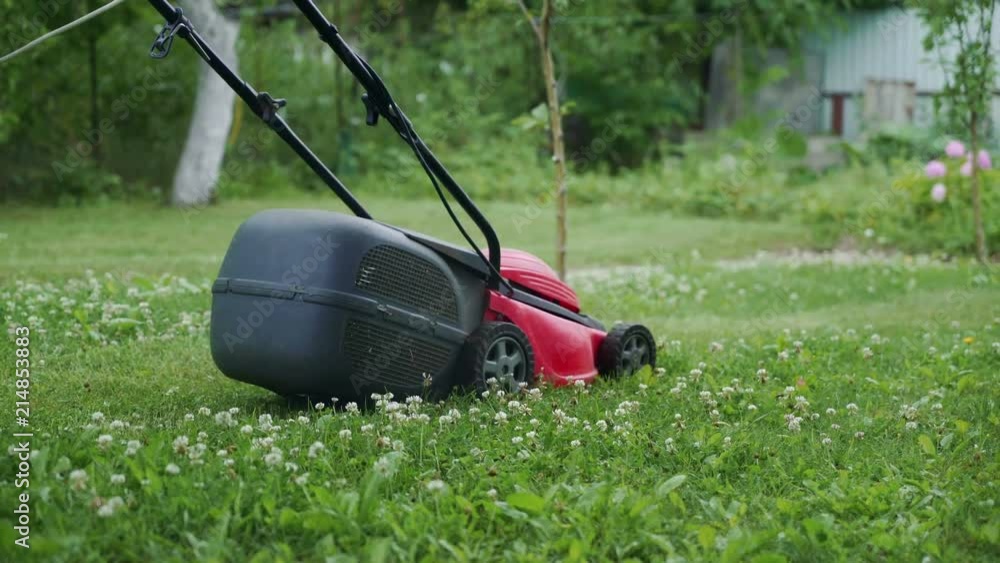Little boy running with a lawn mower in the garden Little boy running with a lawn mower in the garden