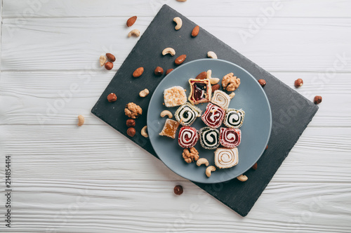 Foto Traditional oriental sweets and nuts: hazelnuts, cashews on a white wooden background