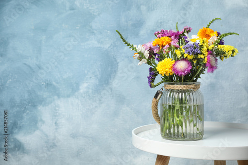 Fototapeta Naklejka Na Ścianę i Meble -  Vase with wild flowers on table against color background