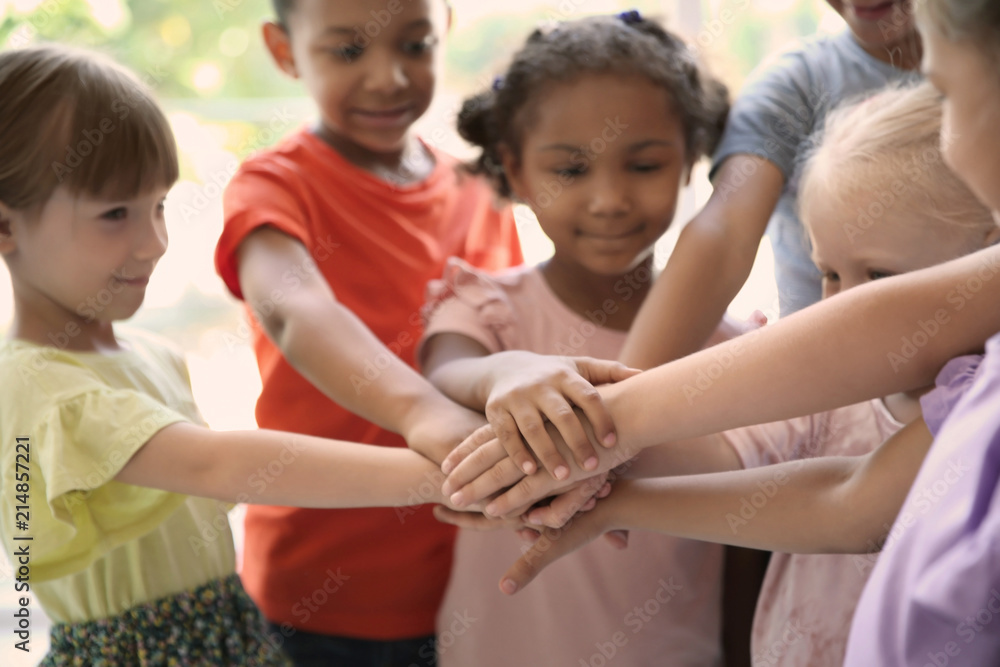 Little children putting their hands together, indoors. Unity concept Little children putting their hands together, indoors. Unity concept