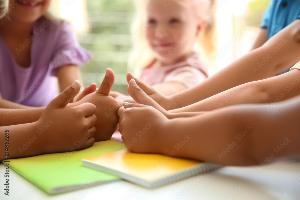 Little children putting their hands together at table, closeup. Unity concept Little children putting their hands together at table, closeup. Unity concept
