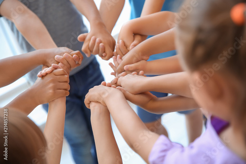 Little children holding their hands together, closeup. Unity concept