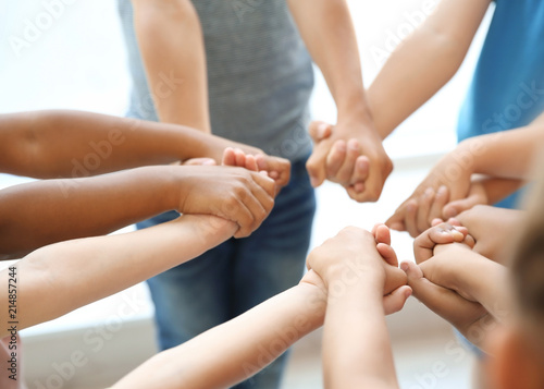 Little children holding their hands together on light background. Unity concept