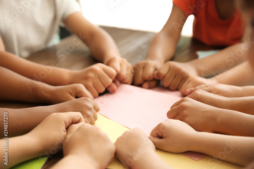 Little children putting their hands together at table  closeup. Unity concept