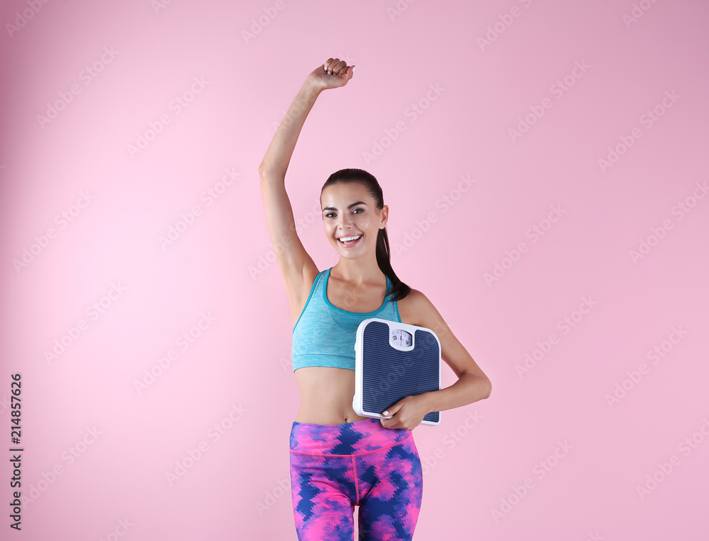 Happy young woman with scales on color background. Weight loss motivation Happy young woman with scales on color background. Weight loss motivation