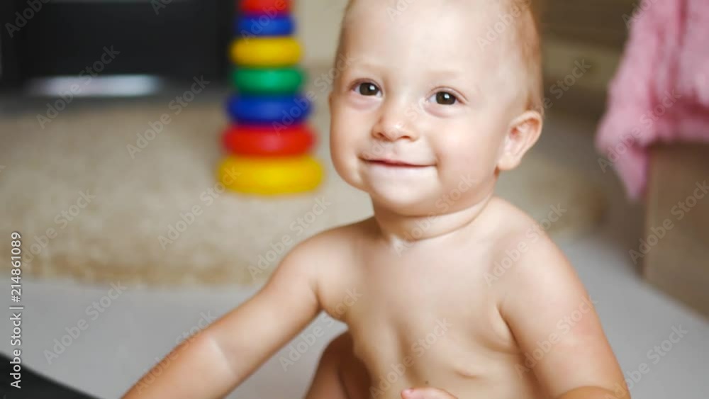 Adorable little happy baby boy is looking into the camera. The baby looks around and then smiles and laughs. Adorable little happy baby boy is looking into the camera. The baby looks around and then smiles and laughs.