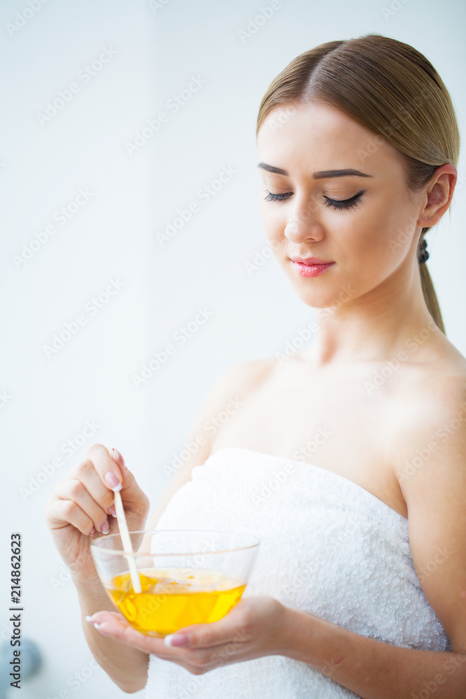Women hold orange paraffin wax bowl. Woman in beauty salon Women hold orange paraffin wax bowl. Woman in beauty salon