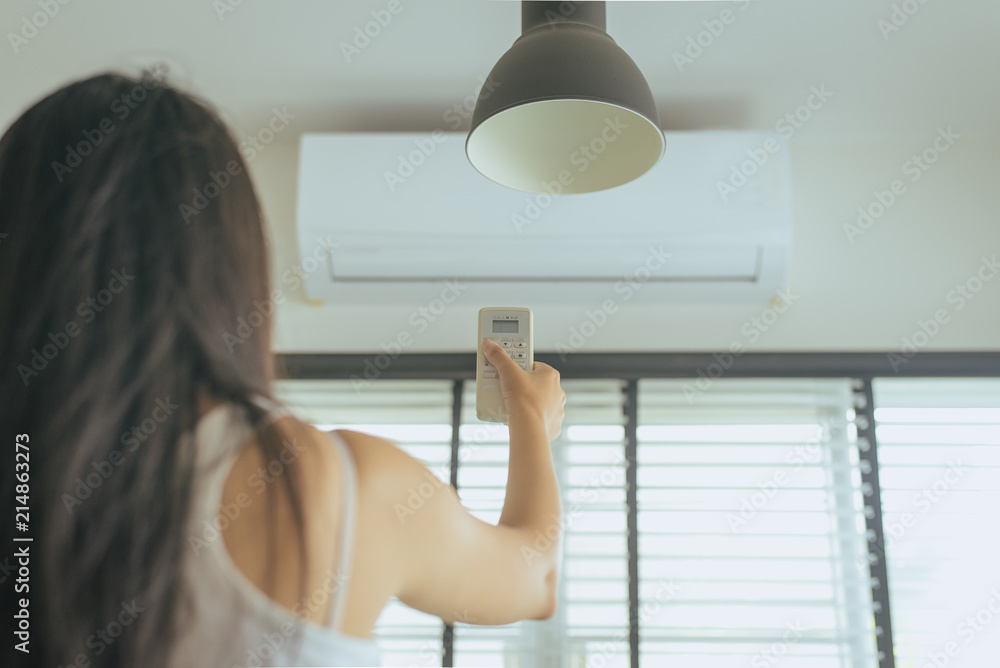 Hand using a remote control to activating air conditioning in room Hand using a remote control to activating air conditioning in room