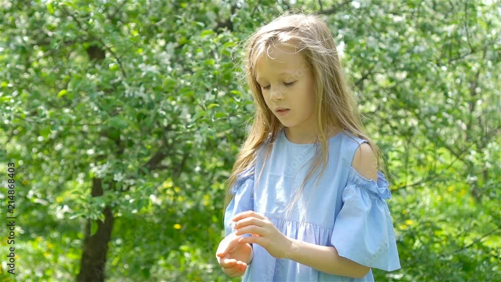 Little girl in blooming apple tree garden on spring day plays with ladybug Little girl in blooming apple tree garden on spring day plays with ladybug