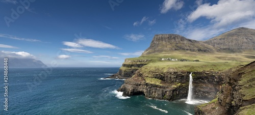 Cliffs with a waterfall near a village, Mykines Island at the rear, Gasadalur, Vagar, Faroe Islands, Denmark, Europe