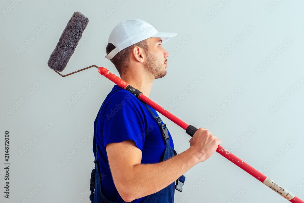 Side View Of Workman Holding Paint Stick Roller. Home improvement concept. Side View Of Workman Holding Paint Stick Roller. Home improvement concept.