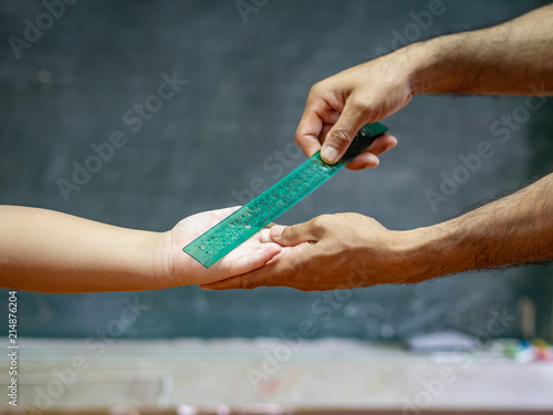 teacher use the ruler hit the kid's hand for punishment.