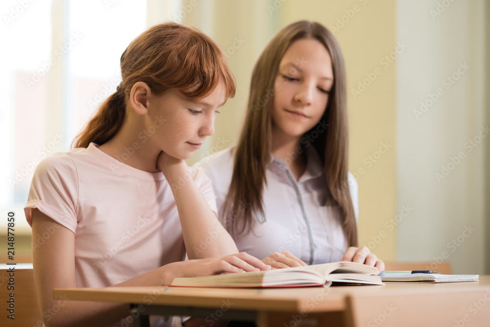 2 student girls are sitting at a Desk 2 student girls are sitting at a Desk