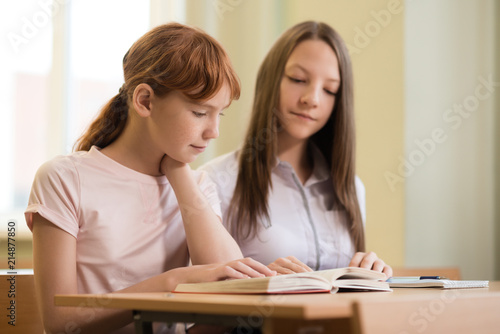 2 student girls are sitting at a Desk