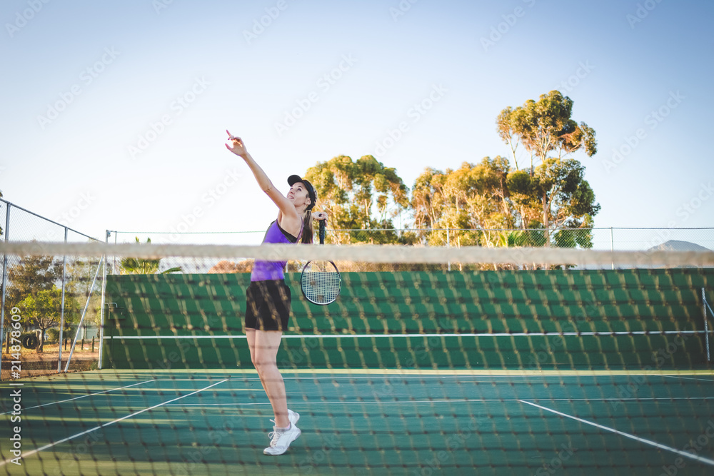 Close up image of a female tennis player playing tennis on a court in bright sunlight